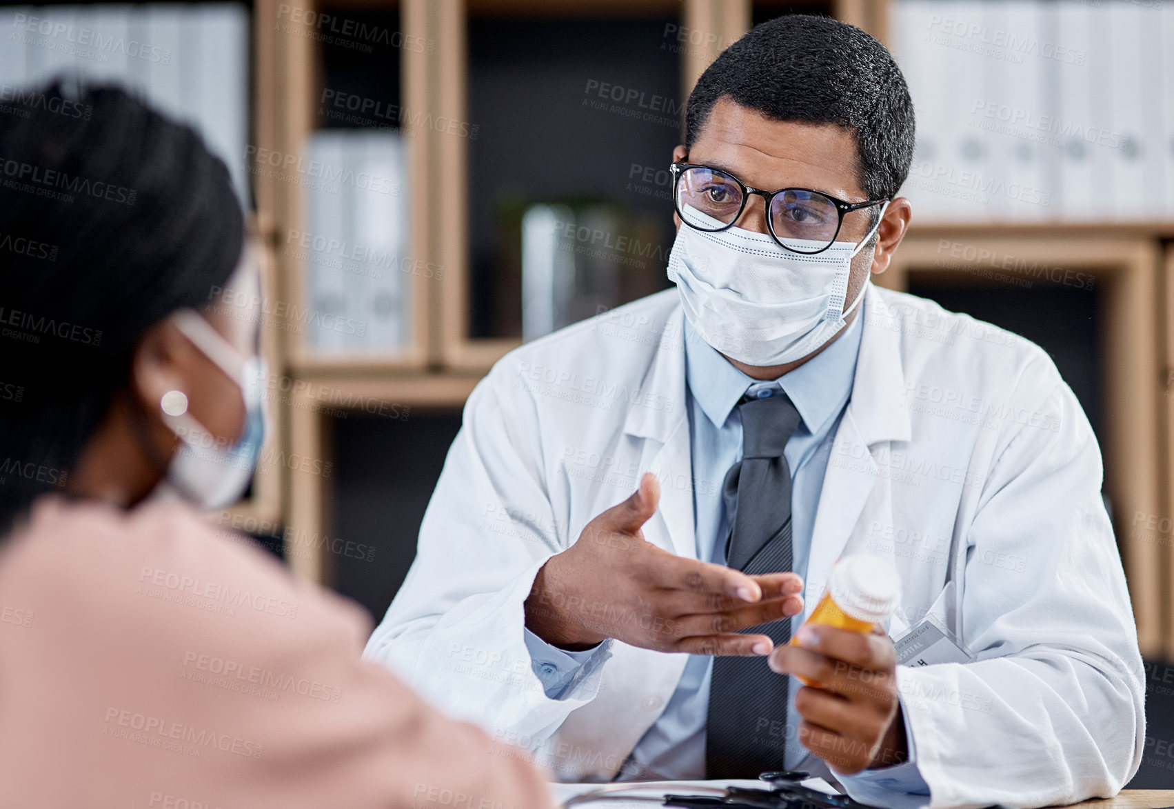 Buy stock photo Medical appointment or doctor consulting a patient during the covid pandemic from his office. Male GP helping a sick client by giving her tablets, medication or medicine and wearing a face mask