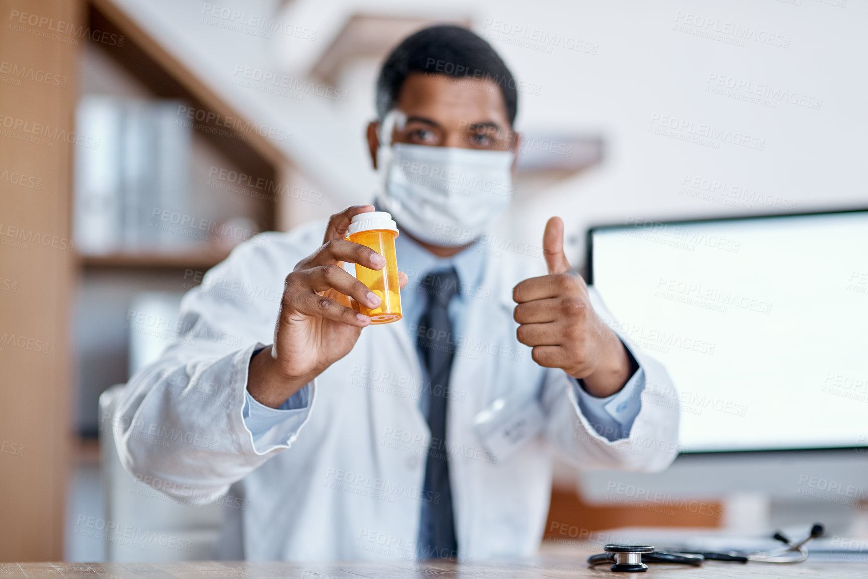 Buy stock photo Portrait of a young doctor holding a bottle of pills and showing thumbs up in his office