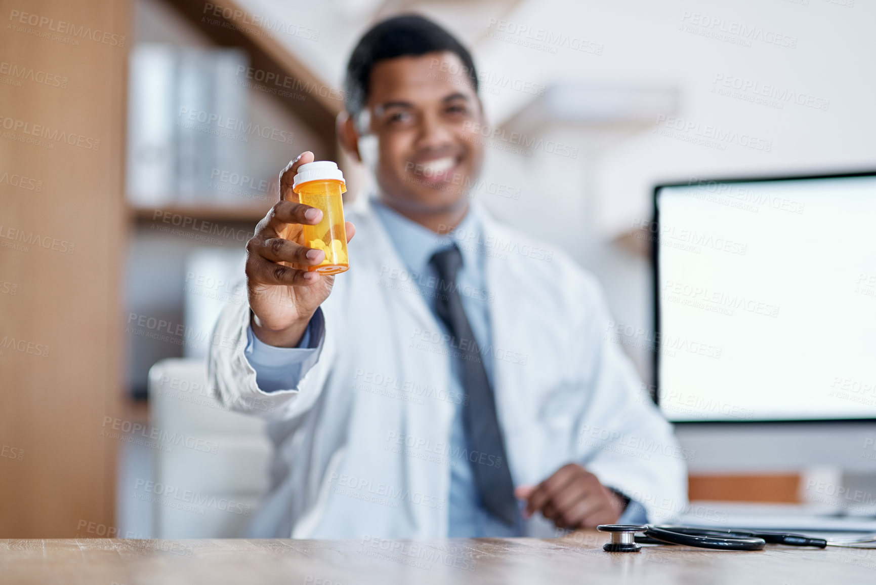 Buy stock photo Happy, joyful and friendly male medical doctor offers a bottle of pills to a client with a smile. Smiling, excited and positive healthcare consultant holding antibiotic medicine sitting at desk. 