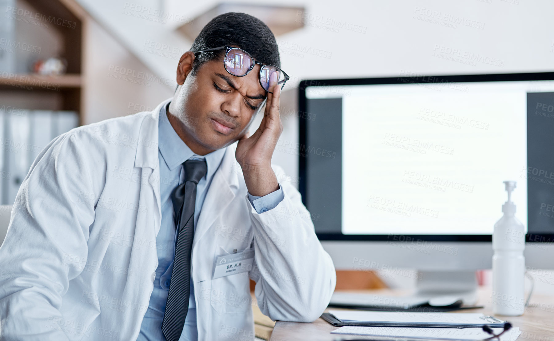 Buy stock photo Doctor suffering from headache, stress and pain while working in a hospital. Young, tired health care professional worker feeling the pressure of a heavy workload during corona virus pandemic 