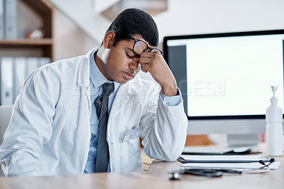 Buy stock photo Stressed, tired young male doctor at his office desk in a hospital. Medical or healthcare man exhausted with pain and headache or sore eyes at the workplace from overworking and burnout