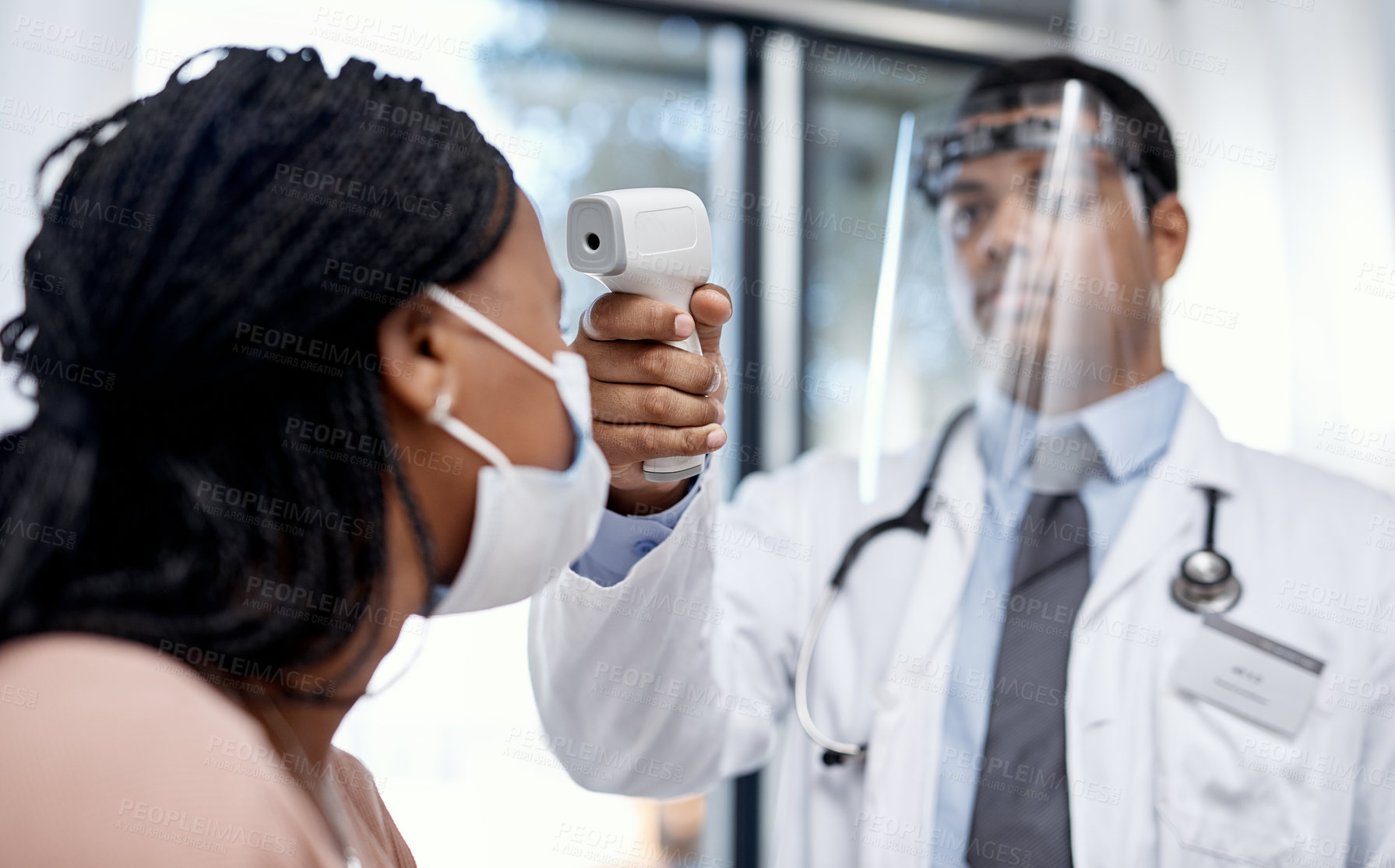Buy stock photo Shot of a doctor taking a patient's temperature with an infrared thermometer