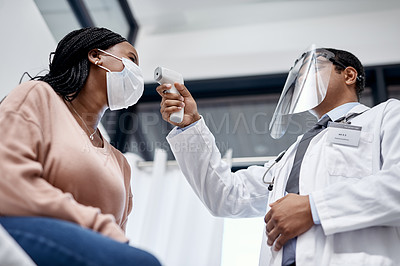 Buy stock photo Covid screening with a doctor measuring temperature of a patient using an infrared thermometer during an appointment or checkup. Female getting tested for corona virus and wearing a mask from below