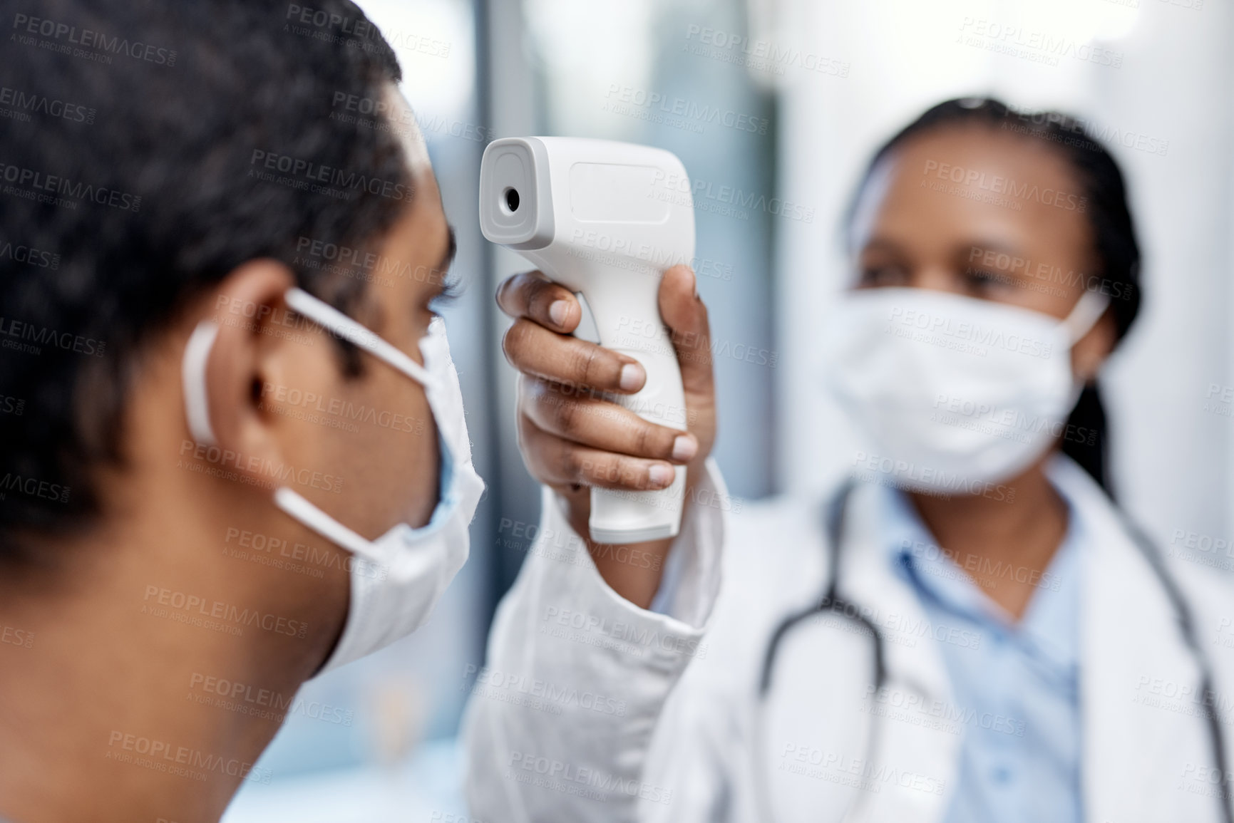 Buy stock photo Shot of a doctor taking a patient's temperature with an infrared thermometer