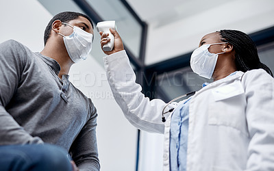 Buy stock photo Female doctor consulting a male covid patient, taking his temperature with infrared thermometer in hospital room or clinic. Man wearing mask and health care professional pointing medical equipment. 