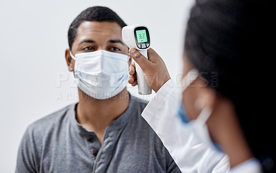Buy stock photo Male covid patient getting his temperature taken with medical equipment by a doctor in hospital consultation room. Man wearing mask and health care professional pointing digital infrared thermometer.
