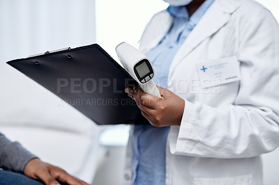 Buy stock photo Closeup shot of an unrecognisable doctor writing notes and holding an infrared thermometer during a consultation with a patient