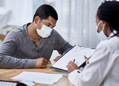 Buy stock photo Shot of a young man going through paperwork during a consultation with a doctor