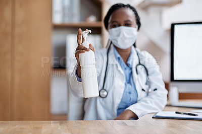 Buy stock photo Portrait of a young doctor holding a bottle of hand sanitiser