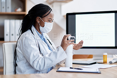 Buy stock photo Shot of a young doctor using hand sanitiser while working in her office