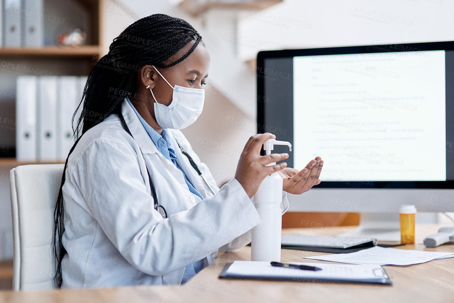 Buy stock photo Shot of a young doctor using hand sanitiser while working in her office