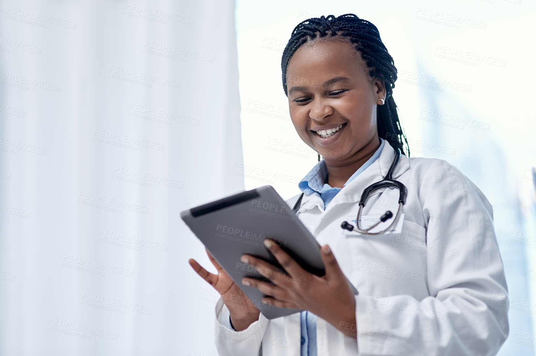 Buy stock photo Shot of a young doctor using a digital tablet in a hospital