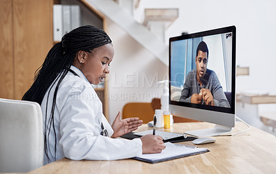 Buy stock photo Shot of a young doctor writing notes during a video call with a patient on a computer