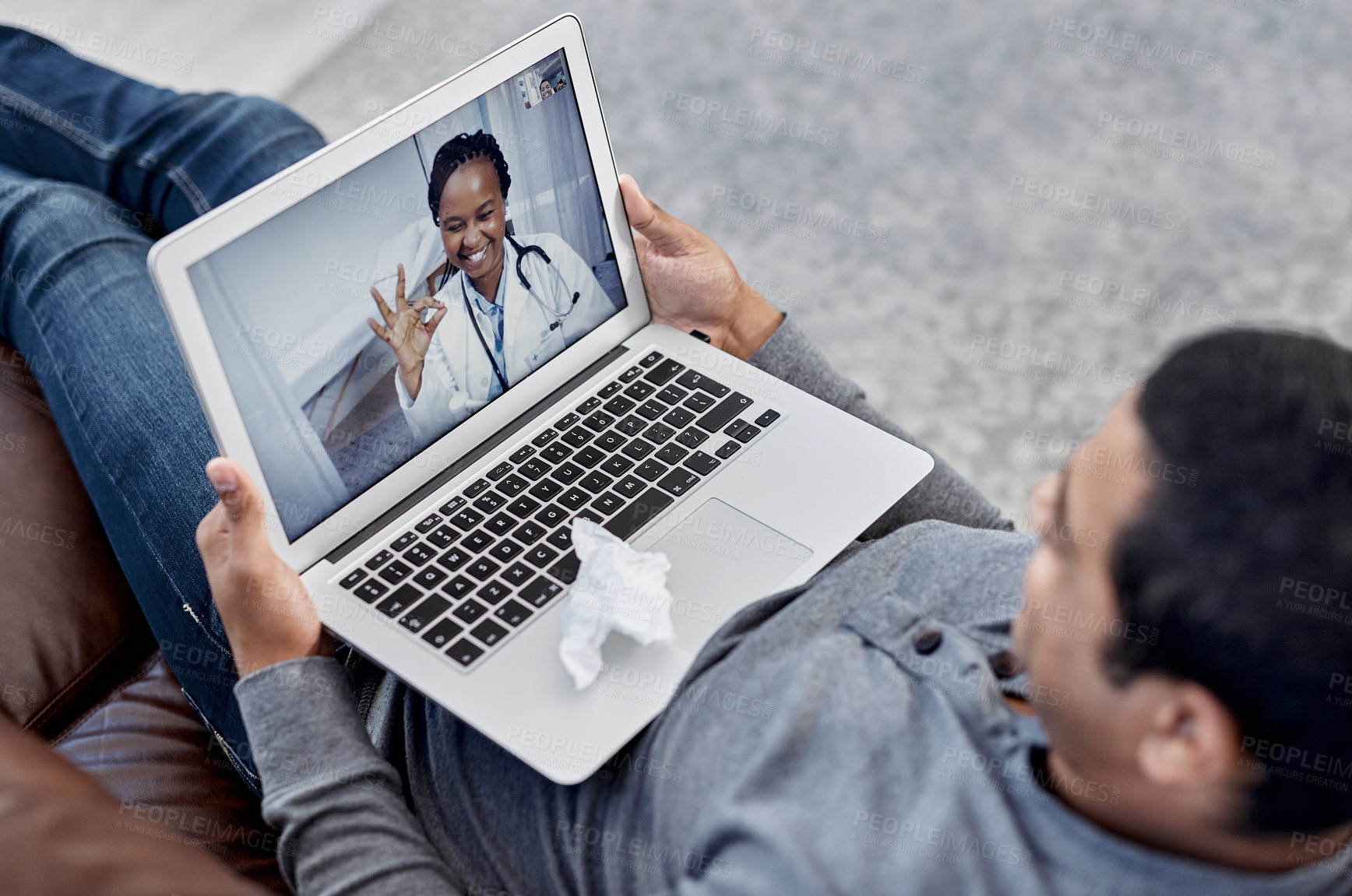 Buy stock photo Shot of a young doctor making an okay sign during a consultation with a patient on a laptop