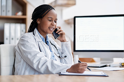 Buy stock photo Shot of a young doctor writing notes while talking on a cellphone in her office