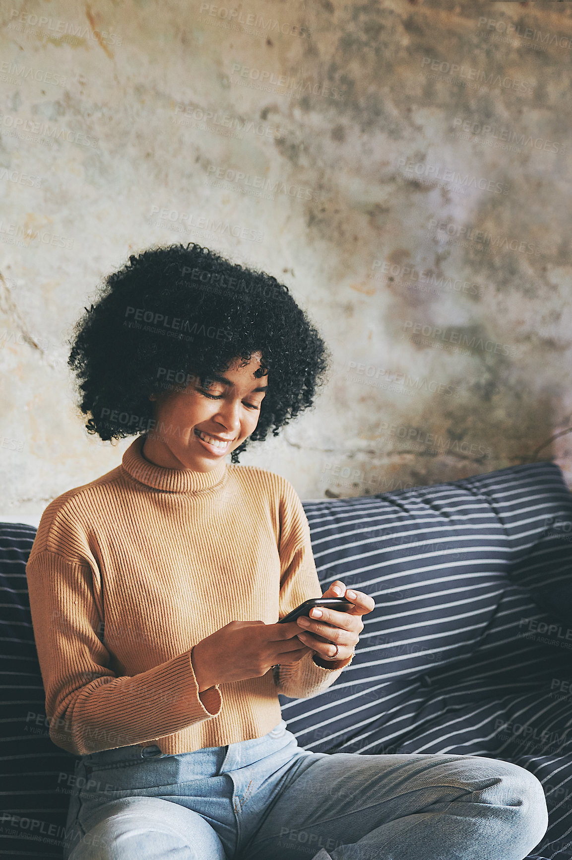 Buy stock photo Shot of a young woman using a cellphone while relaxing on a sofa at home