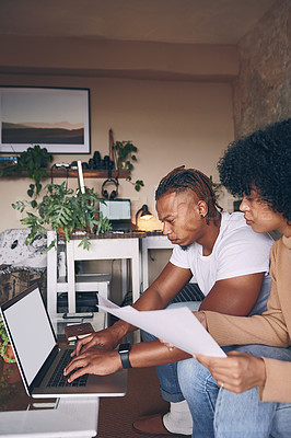 Buy stock photo Shot of a young couple using a laptop while going through paperwork together at home