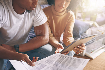 Buy stock photo Shot of a young couple using a digital tablet while going through paperwork together at home