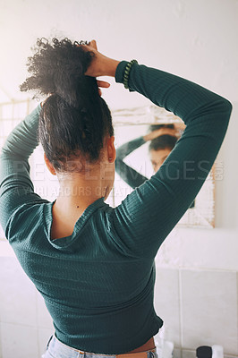 Buy stock photo Rearview shot of a young woman tying her hair in the bathroom at home