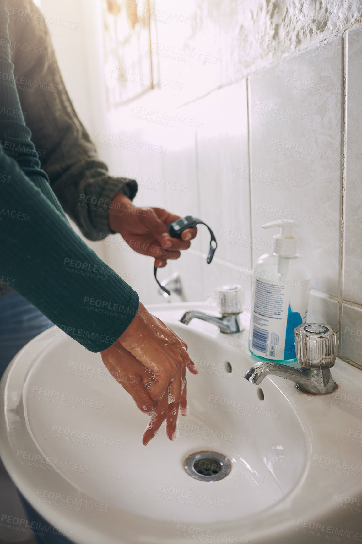 Buy stock photo Closeup shot of an unrecognisable woman washing her hands while being timed with a watch in a bathroom at home