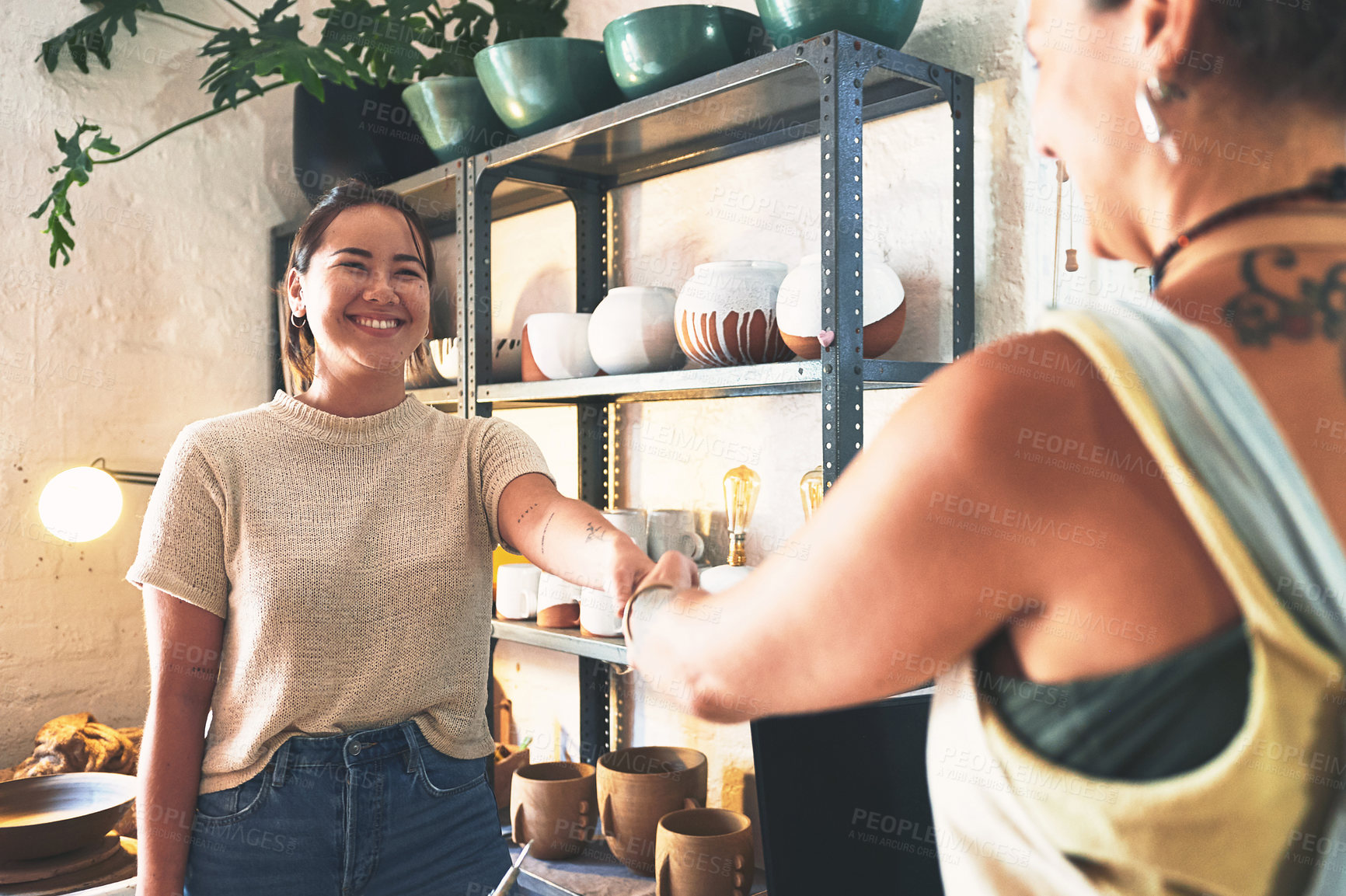 Buy stock photo Shot of two young women shaking hands in a pottery studio