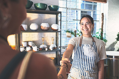 Buy stock photo Shot of two young women shaking hands in a pottery studio