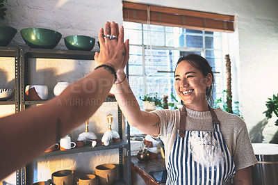 Buy stock photo Shot of two young women giving each other a high five in a pottery studio