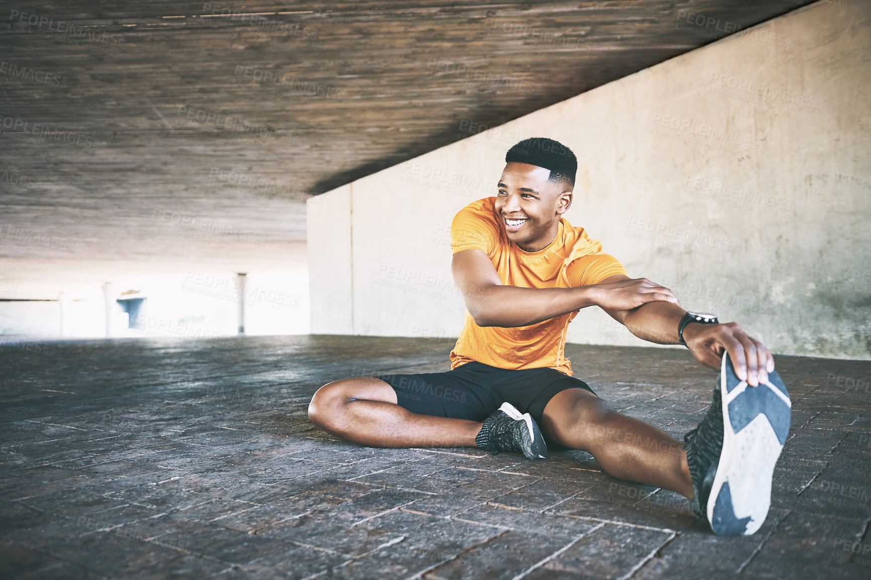 Buy stock photo Shot of a young man stretching during a workout against an urban background