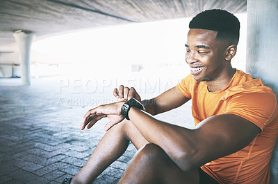 Buy stock photo Shot of a man looking at his watch during a workout against an urban background