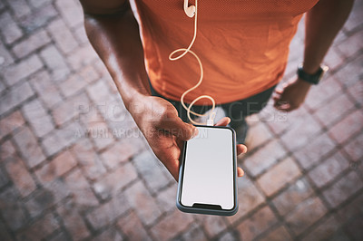 Buy stock photo Cropped shot of a man using a smartphone and earphones during a workout against an urban background