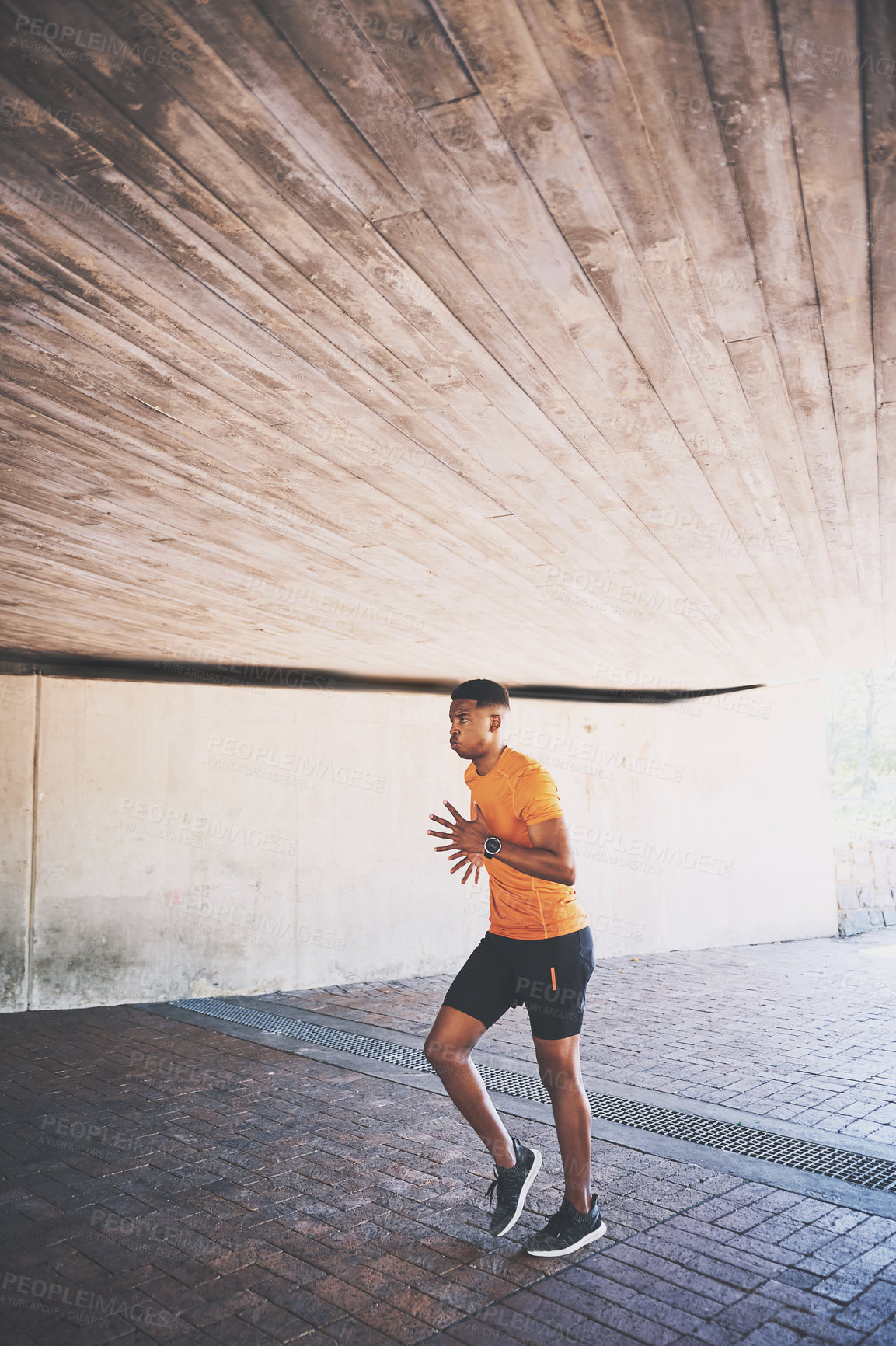 Buy stock photo Shot of a young man going for a run against an urban background