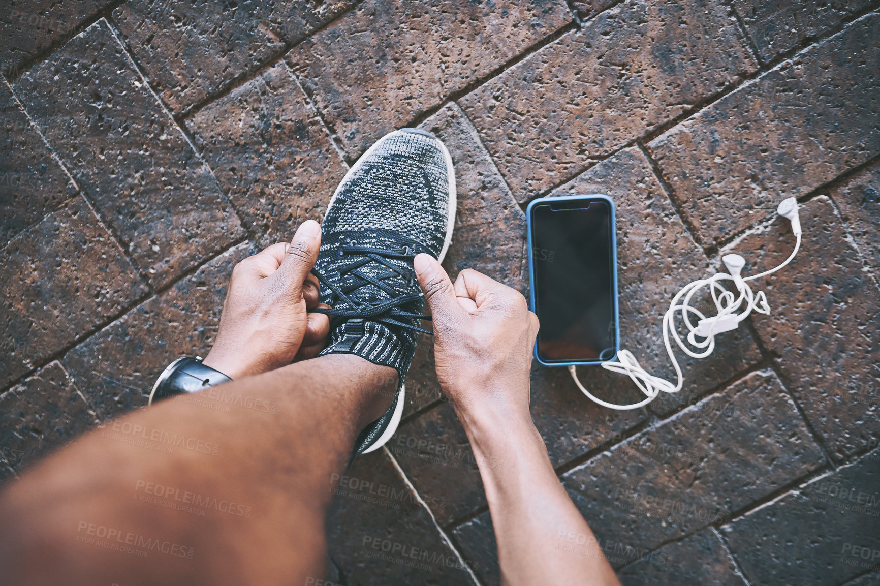 Buy stock photo Cropped shot of a man tying his shoelaces during a workout against an urban background