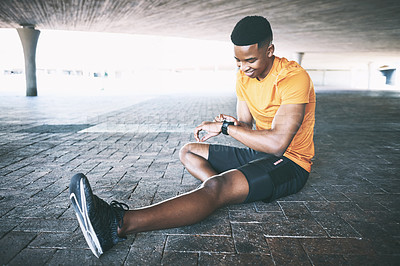 Buy stock photo Shot of a man looking at his watch during a workout against an urban background