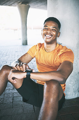 Buy stock photo Portrait of a young man looking at his watch during a workout against an urban background