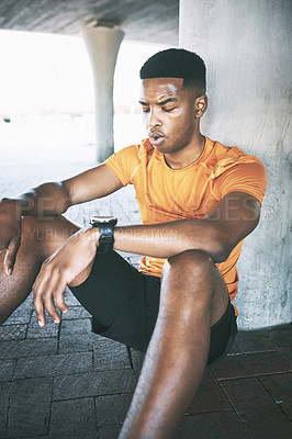 Buy stock photo Shot of a young man taking a break after his workout against an urban background
