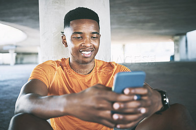 Buy stock photo Shot of a young man using a smartphone during a workout against an urban background