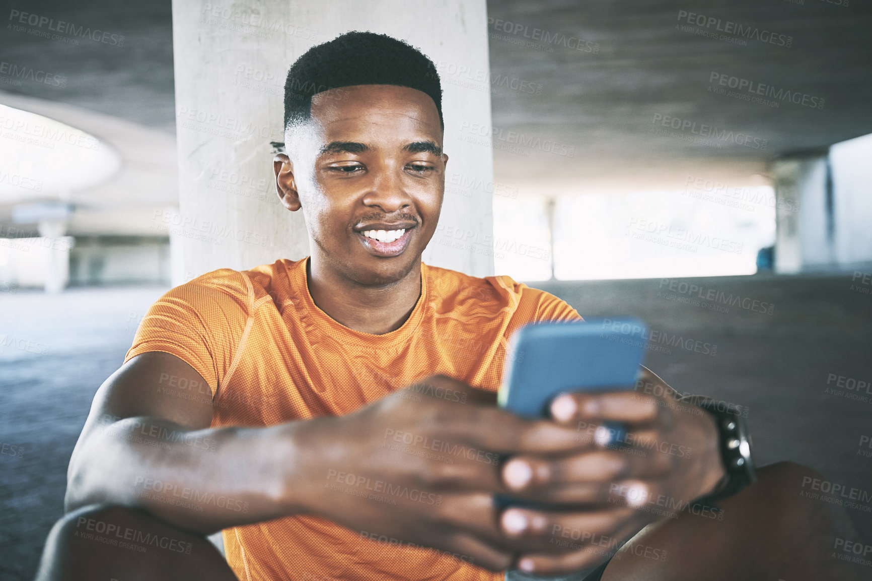 Buy stock photo Shot of a young man using a smartphone during a workout against an urban background