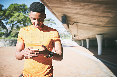 Buy stock photo Shot of a young man using a smartphone during a workout against an urban background