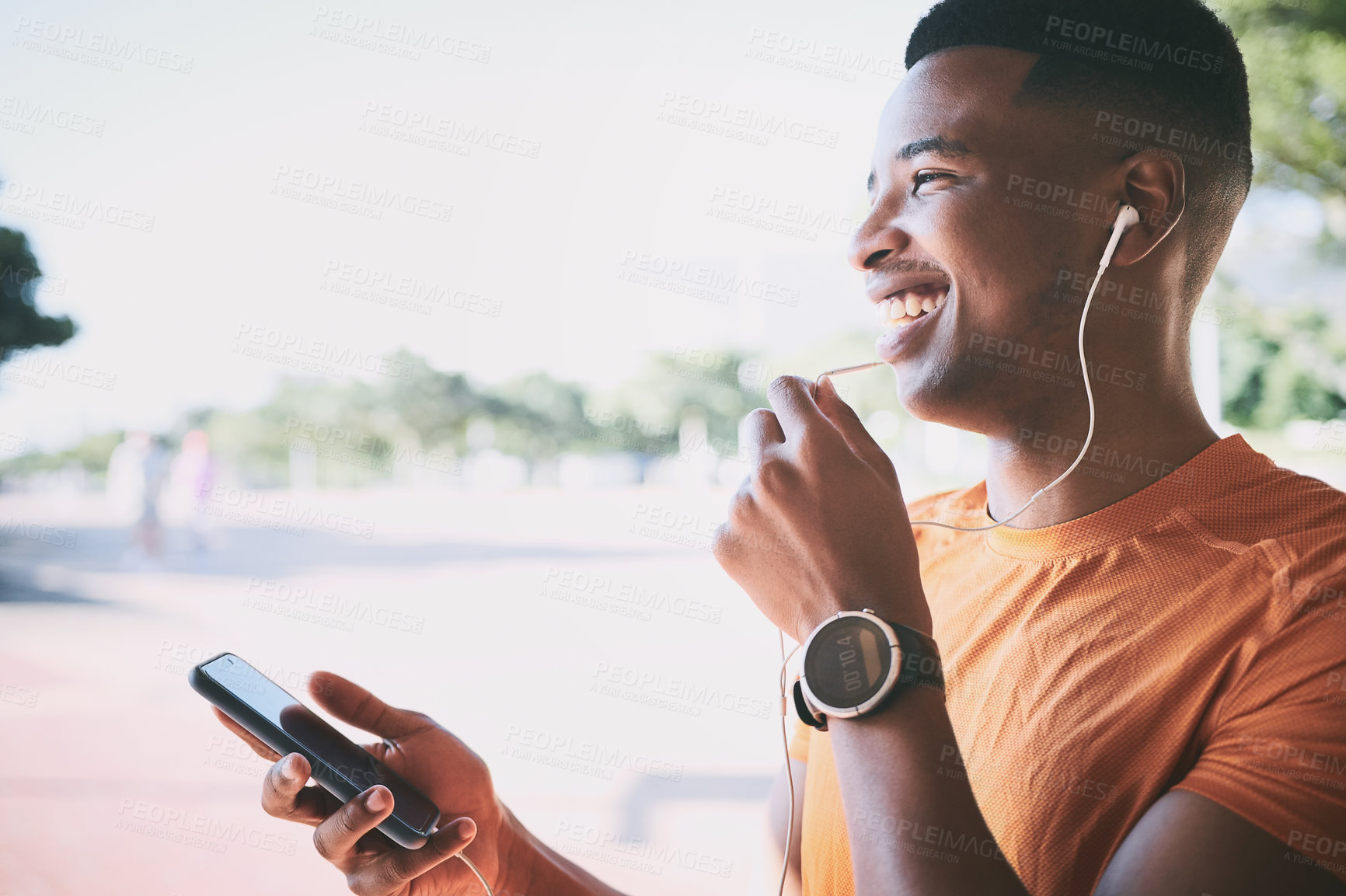 Buy stock photo Shot of a young man using a smartphone and earphones during a workout against an urban background