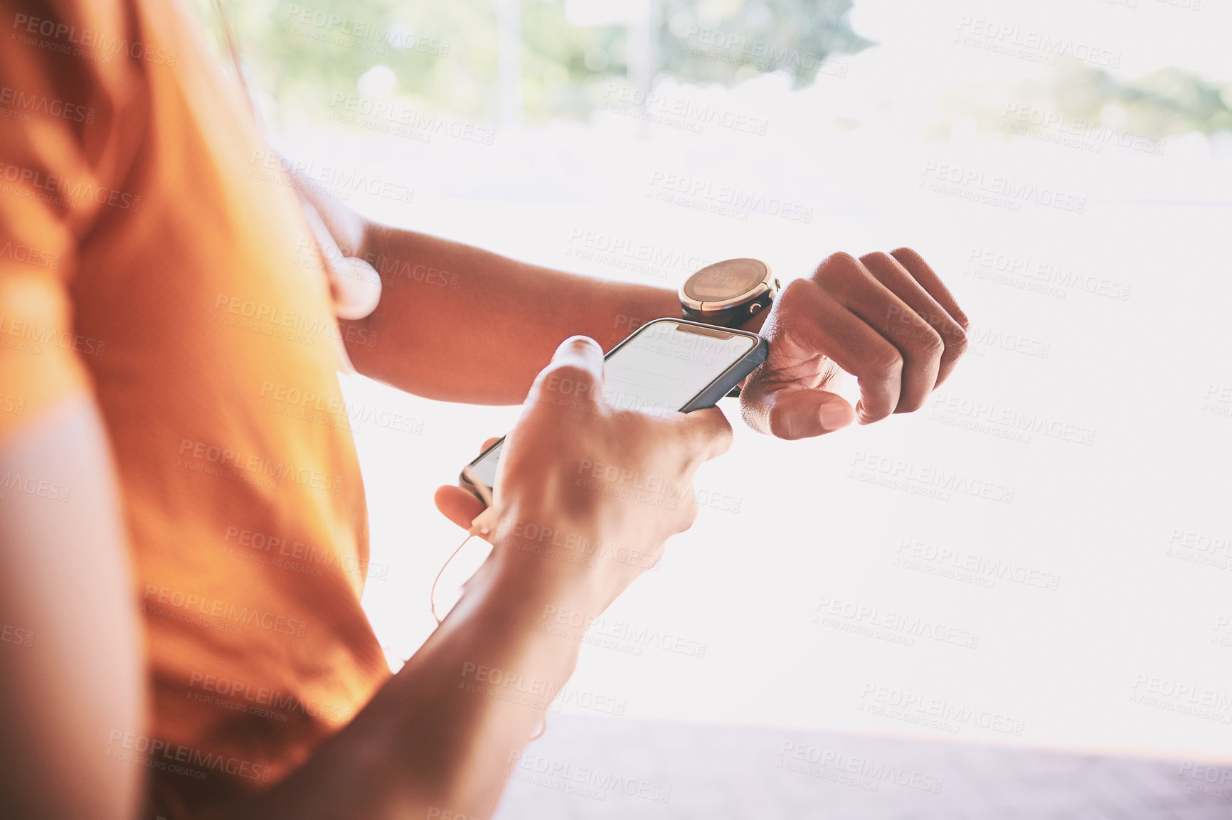 Buy stock photo Shot of a man pairing his watch with a smartphone during a workout against an urban background