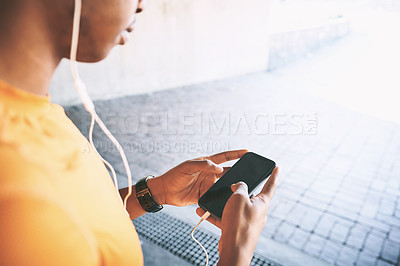 Buy stock photo Cropped shot of a man using a smartphone and earphones during a workout against an urban background