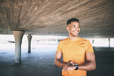Buy stock photo Shot of a man looking at his watch during a workout against an urban background