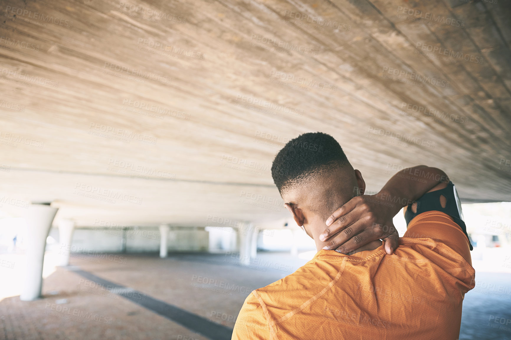 Buy stock photo Rearview shot of a young man experiencing neck pain while working out against an urban background