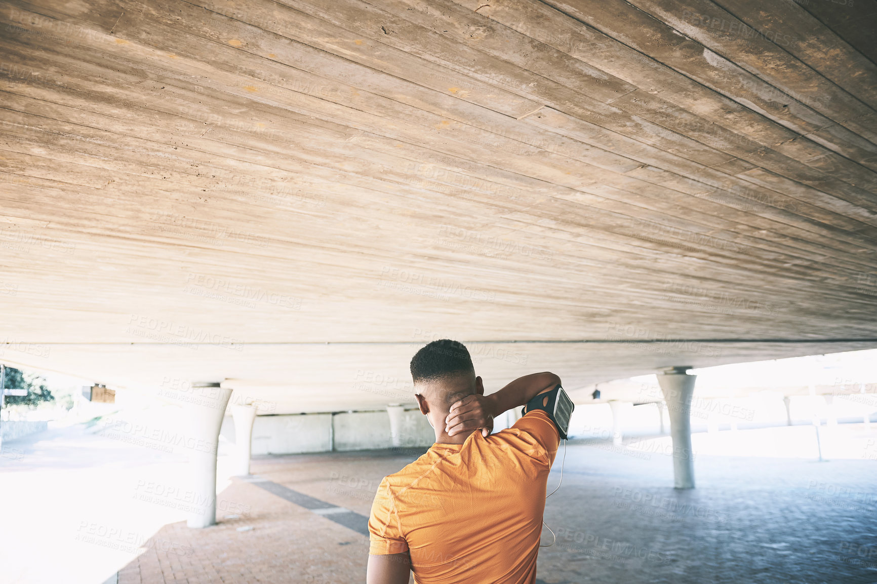 Buy stock photo Rearview shot of a young man experiencing neck pain while working out against an urban background