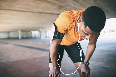 Buy stock photo Shot of a young man taking a break after working out against an urban background