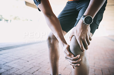 Buy stock photo Cropped shot of a man experiencing joint pain while working out against an urban background