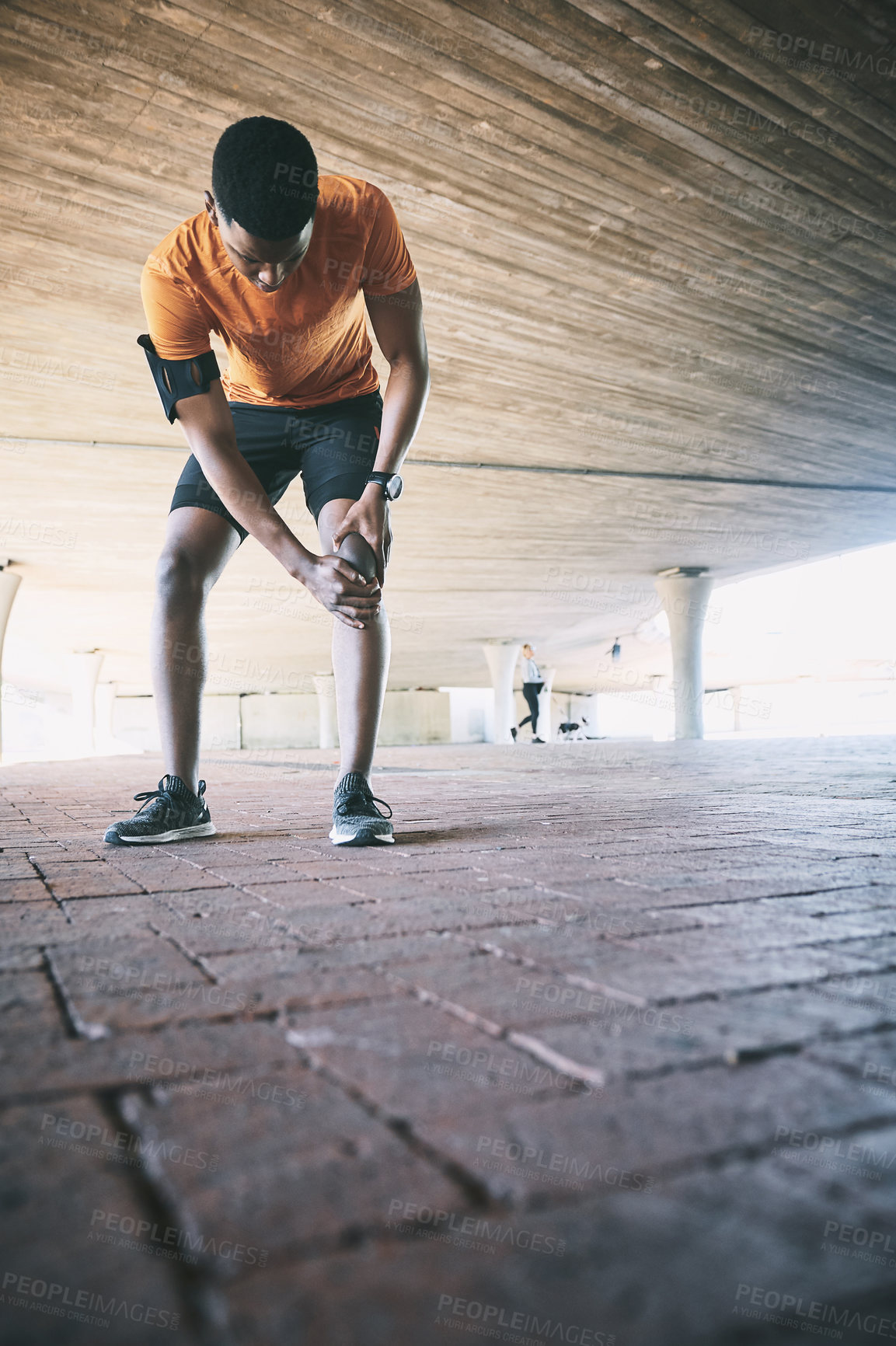 Buy stock photo Shot of a young man experiencing joint pain while working out against an urban background