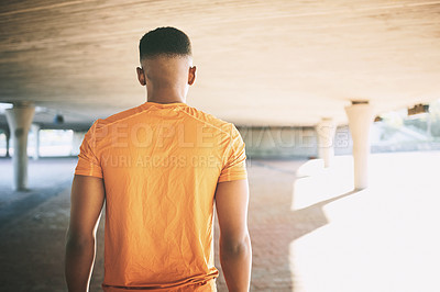 Buy stock photo Rearview shot of a young man working out against an urban background