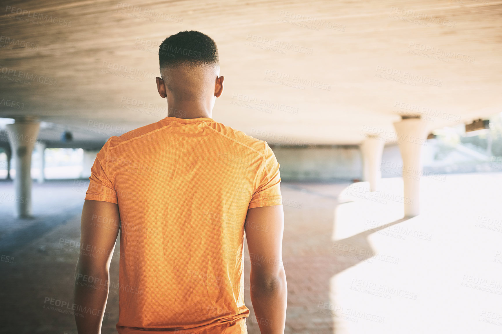 Buy stock photo Rearview shot of a young man working out against an urban background