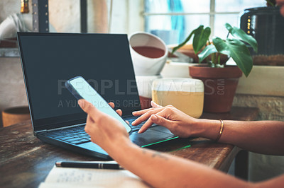 Buy stock photo Cropped shot of an unrecognizable business owner sitting alone in her pottery studio while using her laptop and cellphone